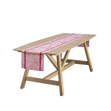 Wooden table with a pink and white patterned table runner on a white background