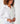 Close up image of the model wearing Tuxedo Ruffle shirt. The top button is unbuttoned, and she has her hands in front of her. She is wearing several gold colored bracelets.