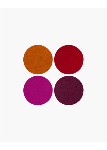 Four textured circular color swatches arranged in a 2x2 grid on a plain white background, showing shades of orange-brown, deep red, magenta, and dark plum.