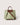 A structured tote bag in light sage green canvas with brown leather handles, trim, and a diagonal shoulder strap, shown on a plain light beige background.