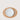 A minimalist tabletop setting featuring a light brown oval placemat with a white ceramic dinner plate and matching white cutlery, photographed from directly above on a light beige background.