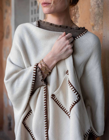 Mersea Whipstitch travel wrap in cream with contrasting bronze stitching. One size, features two front pockets.