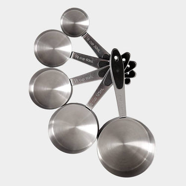 A set of stainless steel measuring cups with black handles, arranged in a fan shape against a light gray background. The metal cups are engraved with volume measurements including 1/4 cup, 1/3 cup, 1/2 cup, 1 cup, and 2 cups.