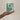Hand holding a plantable seed paper envelope with floral design on a beige background