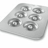 Metal donut baking pan with six circular wells on a white background
