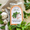 Valente Market roasted garlic and basil fettuccine package with fresh basil and garlic on a textured fabric background