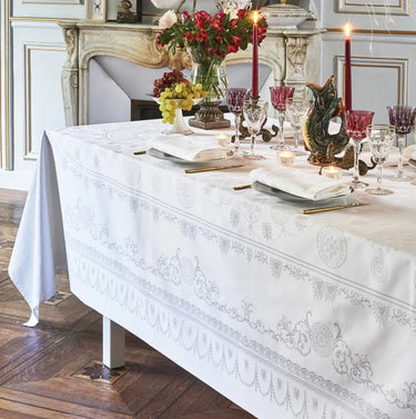Elegant dining table setting with a white tablecloth, candles, and decorative items.