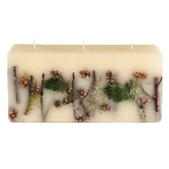 Off-white rectangular candle with three wicks features forest themed botanicals embedded into the wax