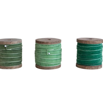 Three ribbon-wrapped wooden spools.  one has an olive green velvet ribbon secured with a pin, one has a spring green velvet ribbon secured with a pin and one has a forest green velvet ribbon, the pin is not shown