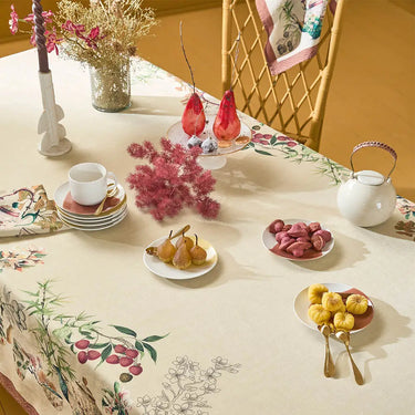 Decorative table setting with floral tablecloth, fruit plates, and teapot on a yellow background