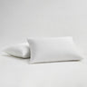 Two bed pillows with white percale pillow cases, one is slightly upright lying on top of the other.