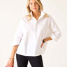 Woman wearing a white blouse and black pants holding a red handbag on a white background