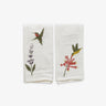 Two white towels with embroidered hummingbird and flower designs on a white background