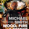 Cover for Michael Smith’s Wood, Fire & Smoke: Recipes and Techniques for Wood-Fired Cooking. Cover features a cast-iron pan, with meat smoking in it