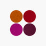 Four textured circular color swatches arranged in a 2x2 grid on a plain white background, showing shades of orange-brown, deep red, magenta, and dark plum.