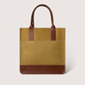 A structured tote bag with a textured mustard-yellow body, brown leather handles, and a brown leather base, shown against a light gray background.