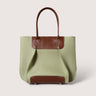 A structured tote bag in light sage green canvas with contrasting brown leather trim, double top handles, and a matching brown base panel, shown against a solid light beige background.