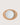 A minimalist tabletop setting featuring a light brown oval placemat with a white ceramic dinner plate and matching white cutlery, photographed from directly above on a light beige background.
