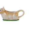 Cow shaped creamer laying on a bed of green grass