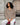 Woman sitting on a red stool wearing white pants and a beige cashmere V-neck sweater