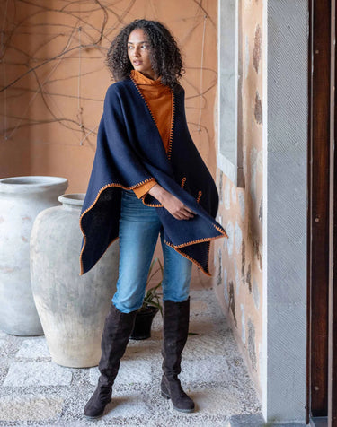 Mersea Whipstitch travel wrap in navy with contrasting golden stitching. One size, features two front pockets.