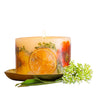 Rosy Rings Petite Botanical Candle in ‘Sugared Citrus.’ Shown on brass candle plate, sold separately. Candle has orange, yellow and green dried floral elements along with slices of orange.