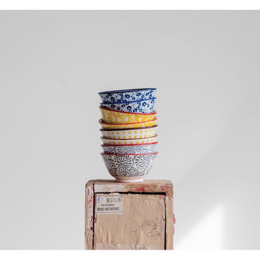 Stack of stoneware pinch pot bowls in grey, yellow, and blue. 