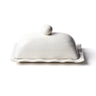 A white ceramic butter dish with a ruffled edge design and a dome-shaped lid.