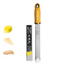 A yellow Microplane Premium Series Zester & Grater with a stainless steel blade and soft-touch handle, displayed alongside a lemon and some grated cheese, against a white background.