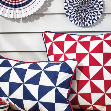 Two geometric-patterned pillows in red, white, and blue on a wooden surface.