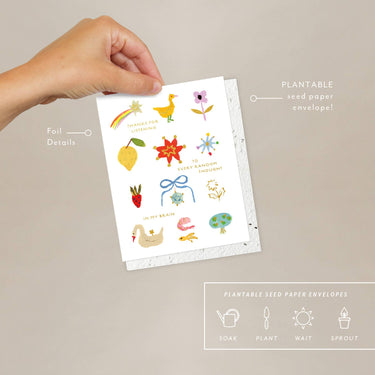Hand holding a plantable seed paper envelope with illustrations on a beige background