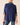 A woman wearing a navy blue cable-knit mock-neck sweater with striped knit cuffs, layered over a matching striped mock-neck shirt, paired with blue jeans against a plain beige background.