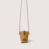 A mustard yellow canvas bucket bag with brown leather trim and a long brown shoulder strap, shown against a solid light beige background.