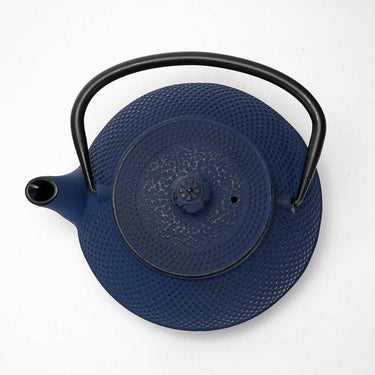 Blue cast iron teapot with black handle on a white background